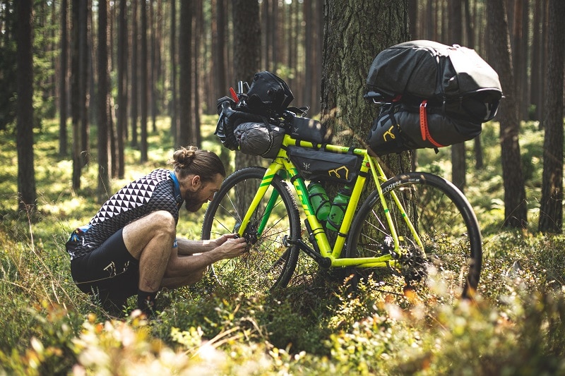 Mann repariert sein Mountainbike während einer Tour im Gelände