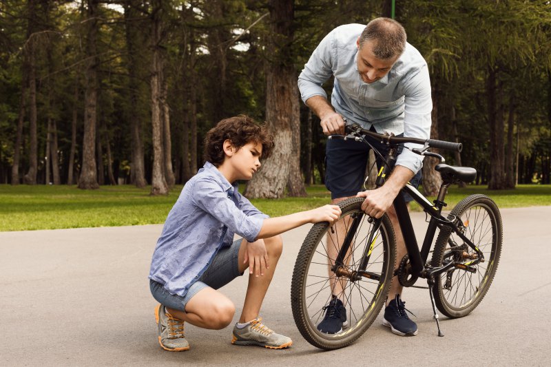 Vater und Sohn prüfen Reifendruck um Reifen mit Fahrrad-Standpumpe aufzupumpen